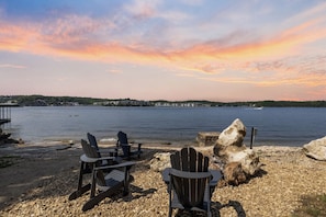 A lakeside view with chairs and a rocky shore.