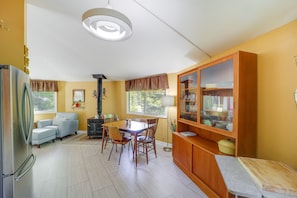 A compact kitchen with a dining area, a refrigerator, a sofa, and a cabinet with glass doors.