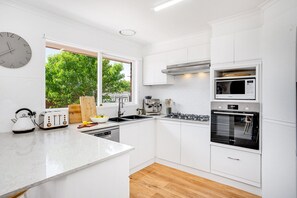 Kitchen features a gas stove, oven, microwave, coffee maker, and toaster on a large island countertop.