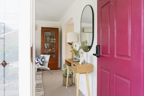Enter a cozy space with a stylish cabinet, comfortable chair, and a small table with a lamp.