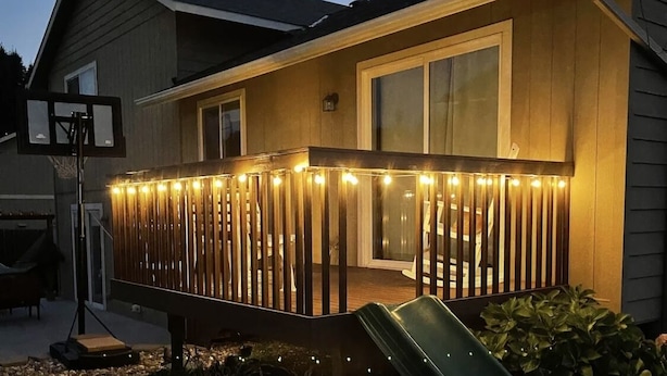 Una casa con terraza de madera, aro de baloncesto y tobogán.
