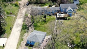 An aerial view of a residential area with multiple houses, a dirt road, and a small clearing with a fire pit. - 4 Unique Cottages Sleeps 16 Comfortably on 1 Acre (Coloma)