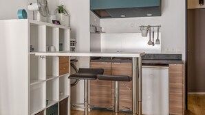 Uma cozinha compacta com ilha central, banquetas e eletrodomésticos modernos.