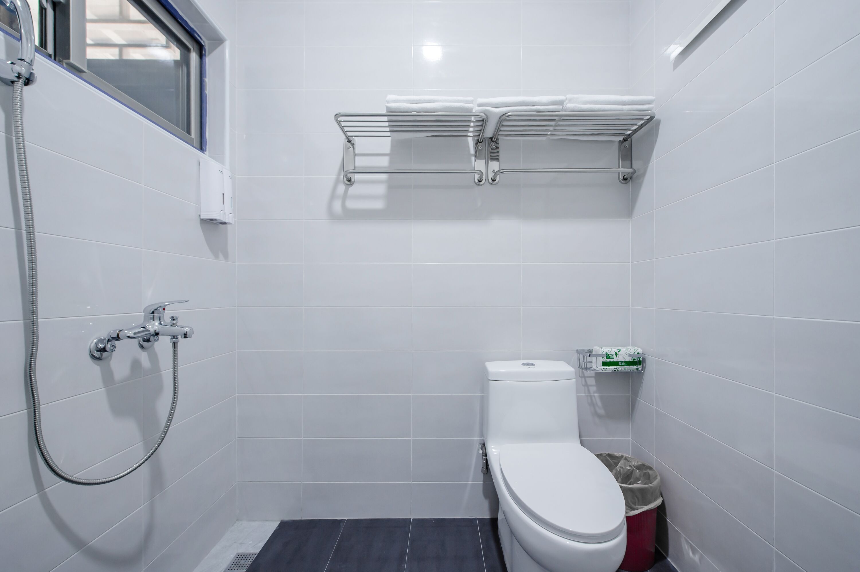 A bathroom with a toilet, a shower, and a towel rack.