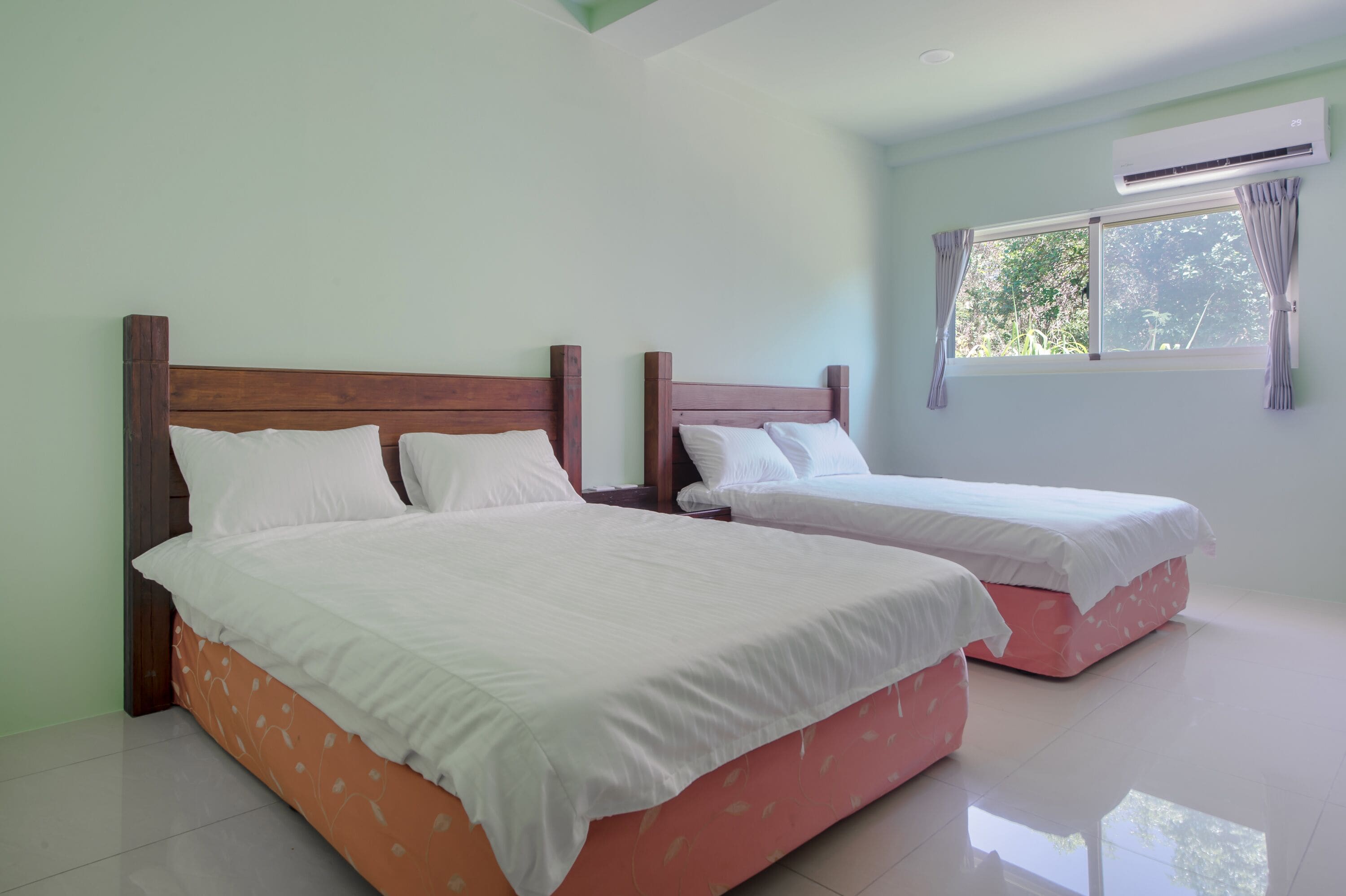 Habitación de hotel con dos camas, una ventana con cortinas e un equipo de aire acondicionado.