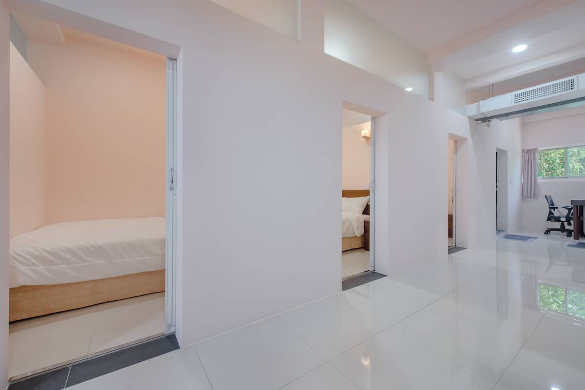 A modern hotel room with a large bed, a desk, and a chair. There is a window with a view of greenery outside.