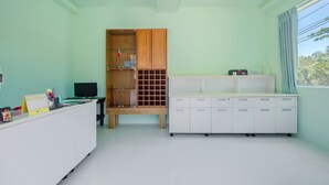 Um quarto com uma escrivaninha, um computador, um armário de madeira e um móvel de armazenamento branco.