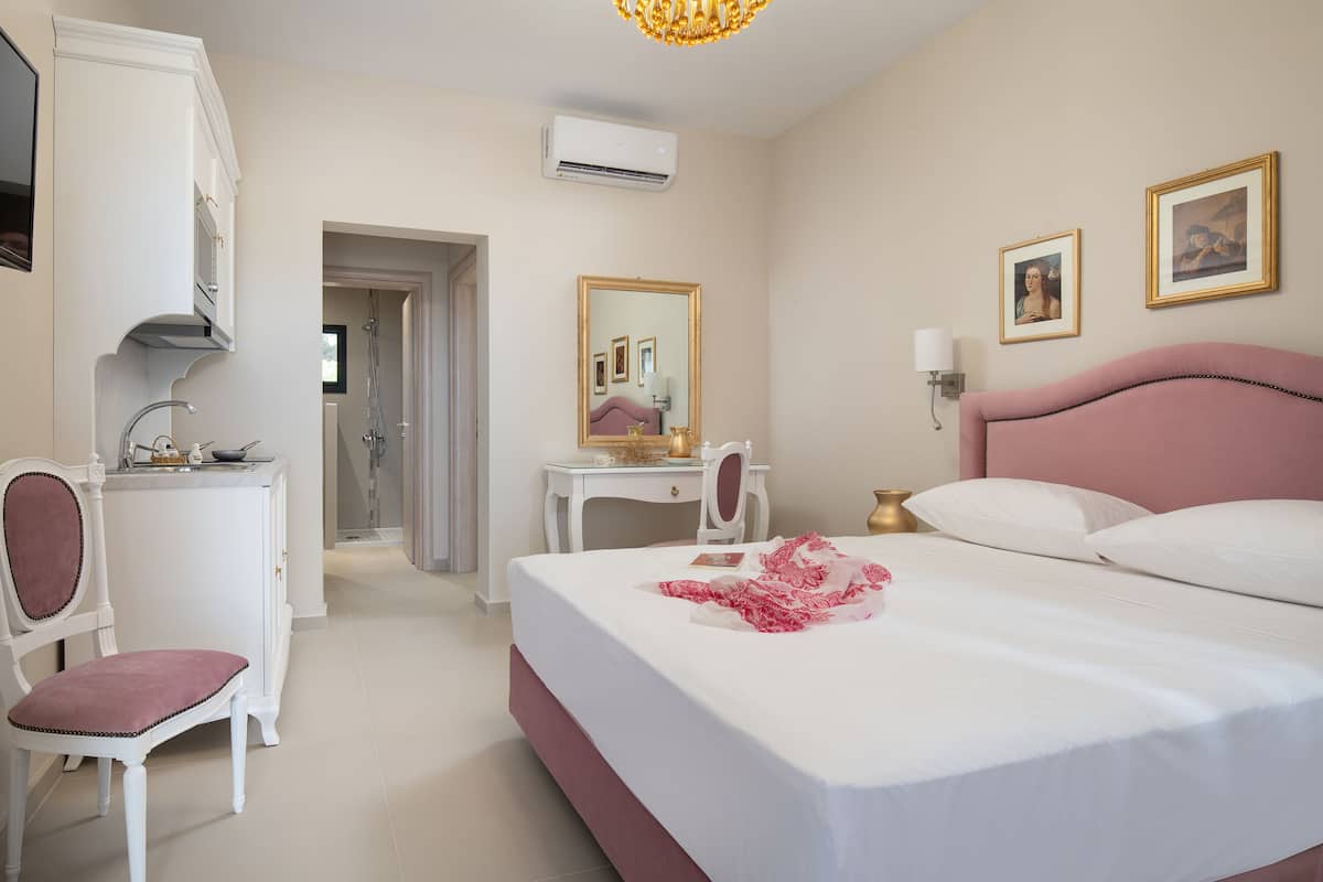 A hotel room with a large bed, a desk, a chair, and a mirror.