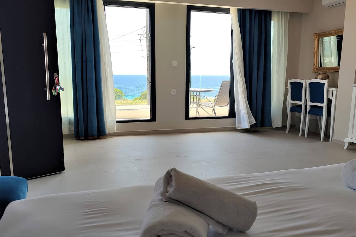 A hotel room with a bed, a desk, and a view of the sea.