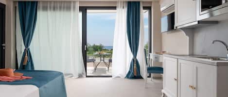 A hotel room with a bed, a kitchenette, a dining area with a table and chairs, and a view of the outdoors.