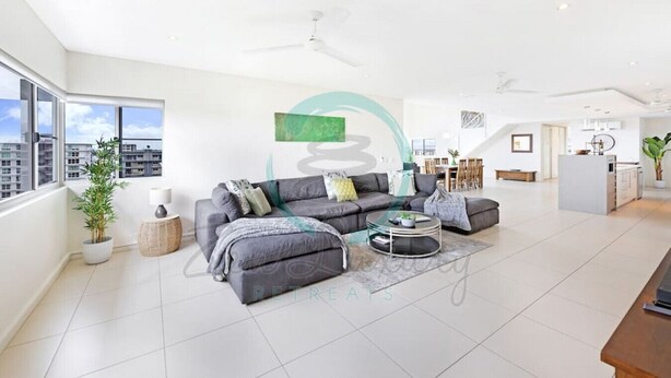 A modern living room with a grey sofa, a coffee table, and a dining area in the background. - ZEN LUXURY 2-STORY Penthouse Mindal View (Darwin)