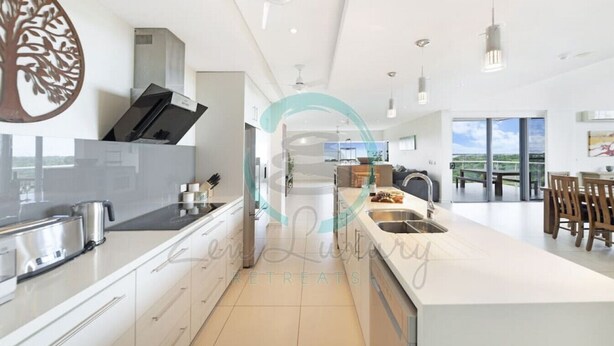 Una cocina moderna con una isla central, electrodomésticos de acero inoxidable y vistas al balcón exterior.