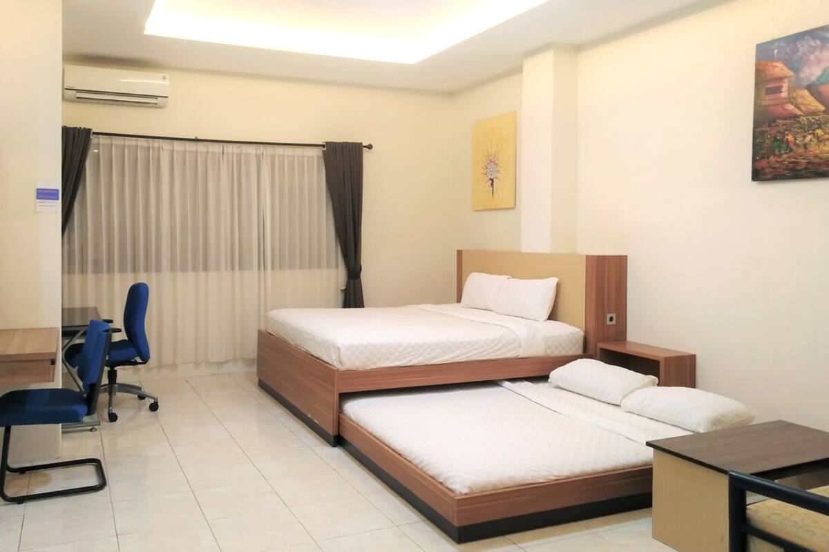 Ein Hotelzimmer mit zwei Betten, einem Schreibtisch, einem Stuhl und einem kleinen Tisch.