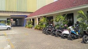 Un edificio con techo de tejas rojas y un estacionamiento con varias motocicletas.