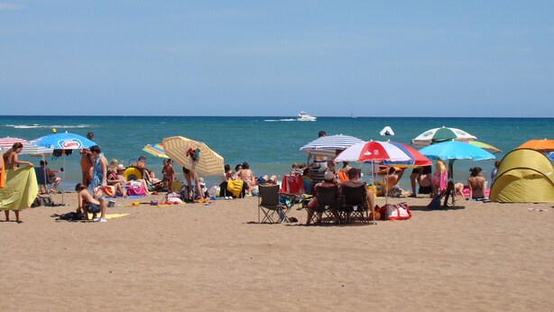 Une plage avec des gens, des parasols et une tente.