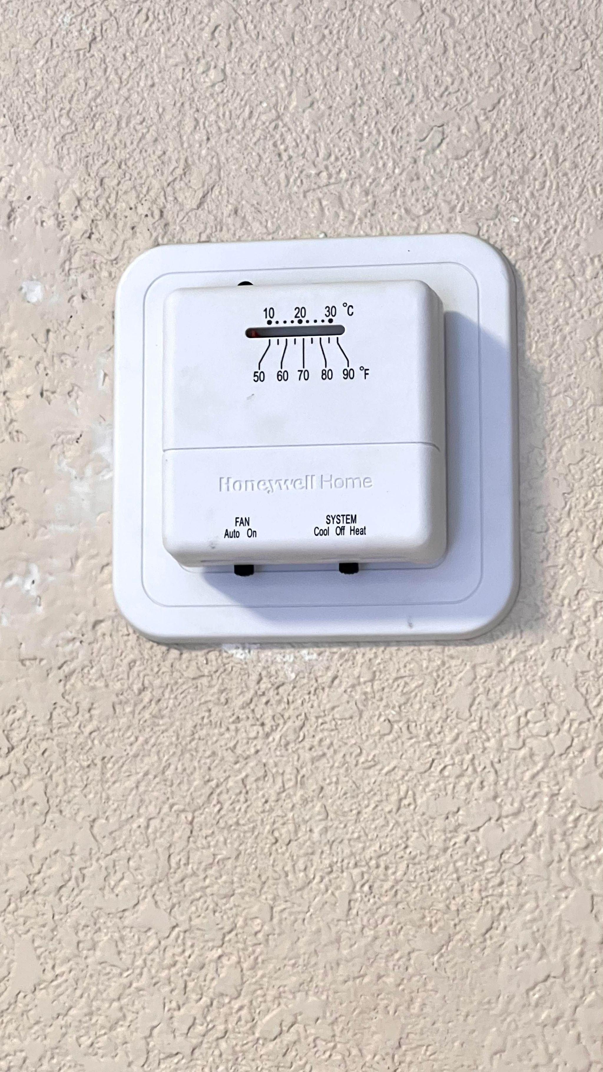 Un termostato Honeywell Home con configuraciones de temperatura en grados Celsius y Fahrenheit, etiquetado como 'FAN Auto On' y 'SYSTEM Cool Off Heat'.