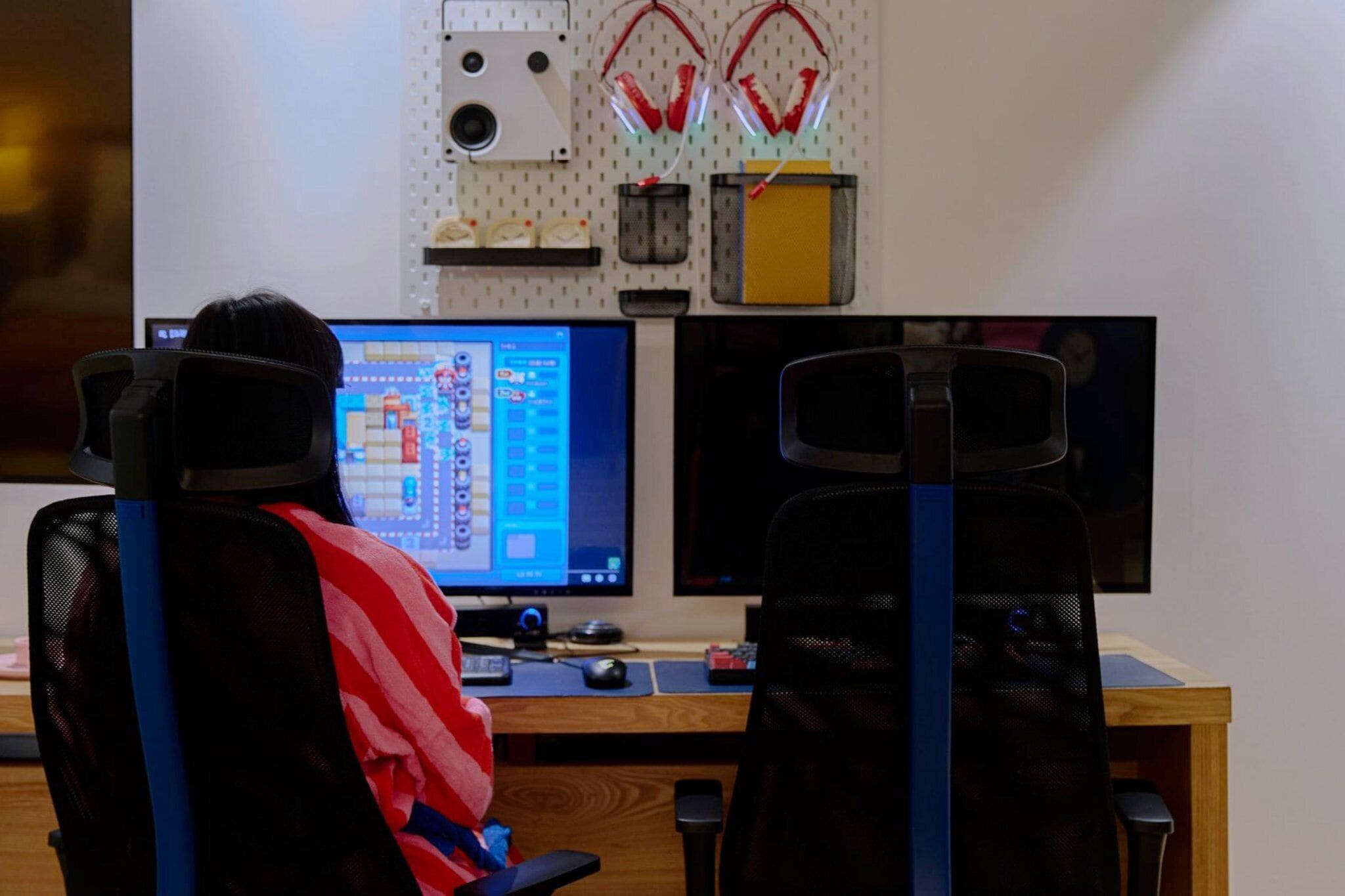A workspace with two monitors, a desk, and a chair.