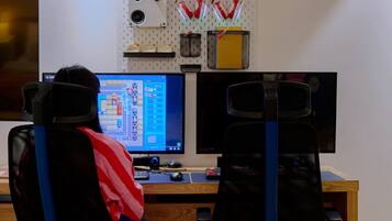 A workspace with two monitors, a desk, and a chair.