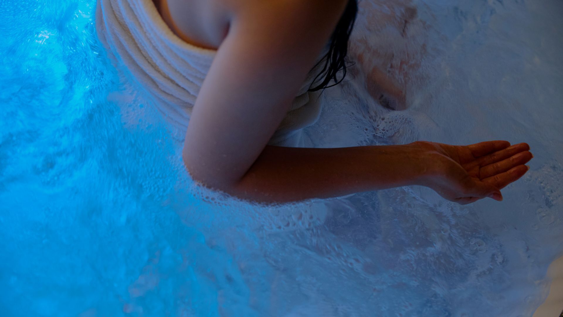 A person in a bathtub with blue lighting.