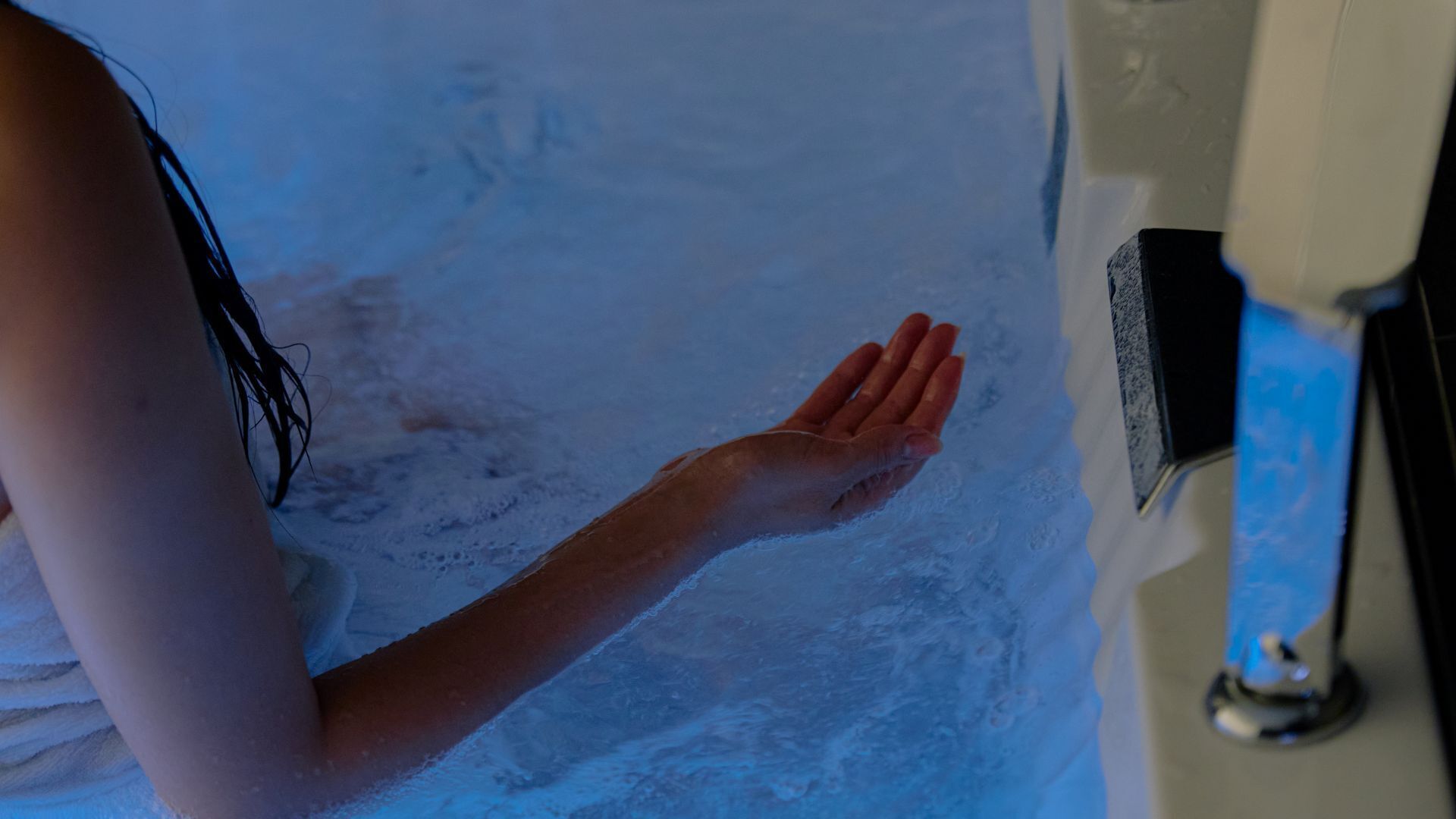 Eine Person in einer Badewanne mit blauem Licht, umgeben von Wasser.