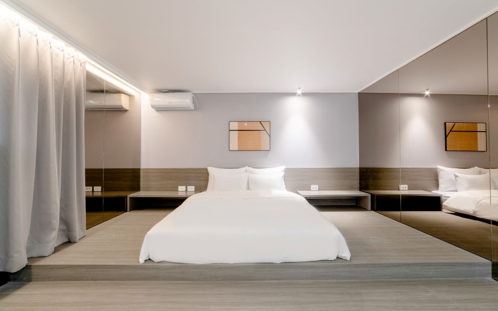 A hotel room with a large bed, two bedside tables, a headboard, and a large mirror.