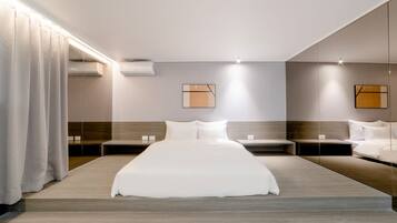 A hotel room with a large bed, two bedside tables, a headboard, and a large mirror.