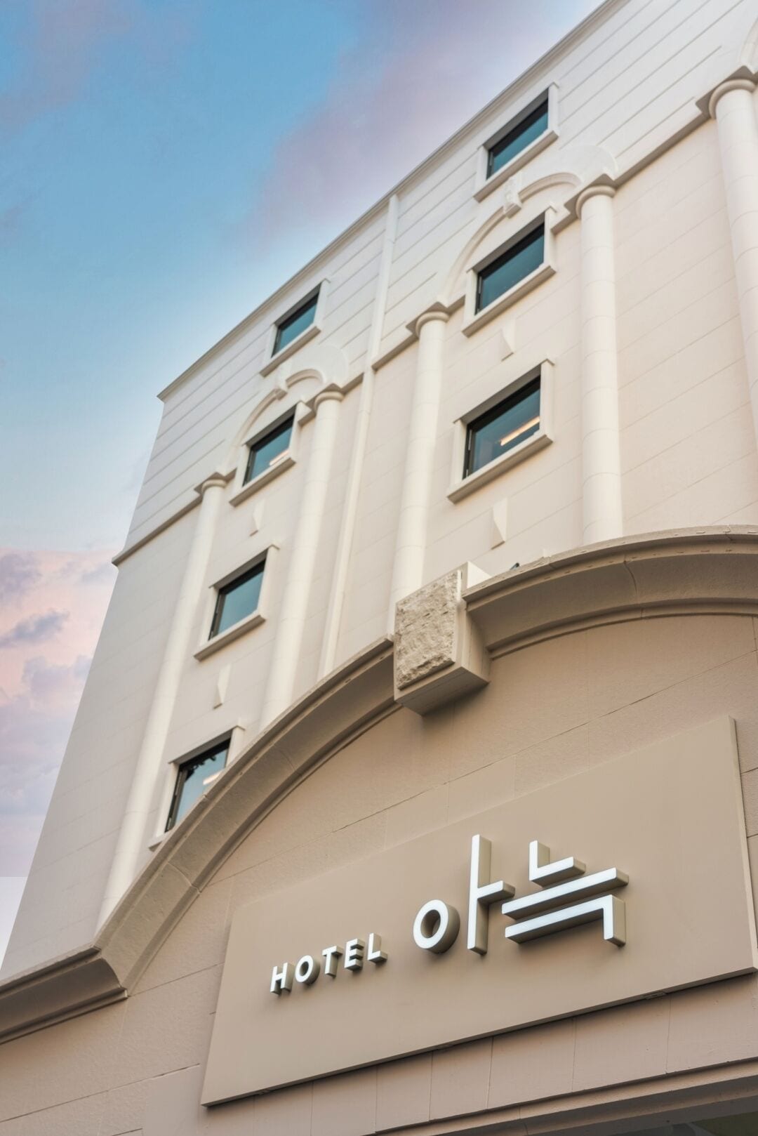 A hotel building with a modern facade, multiple windows, and a prominent "HOTEL" sign.