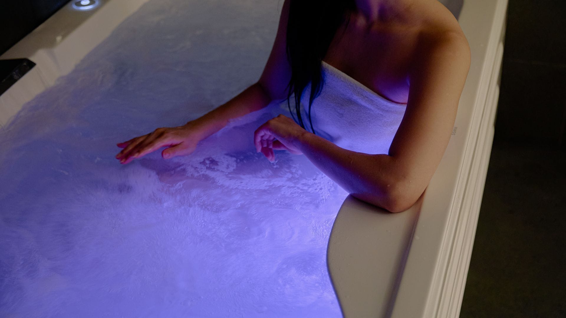 A person in a bathtub with a purple light.