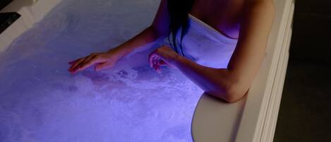 A person in a bathtub with a purple light.