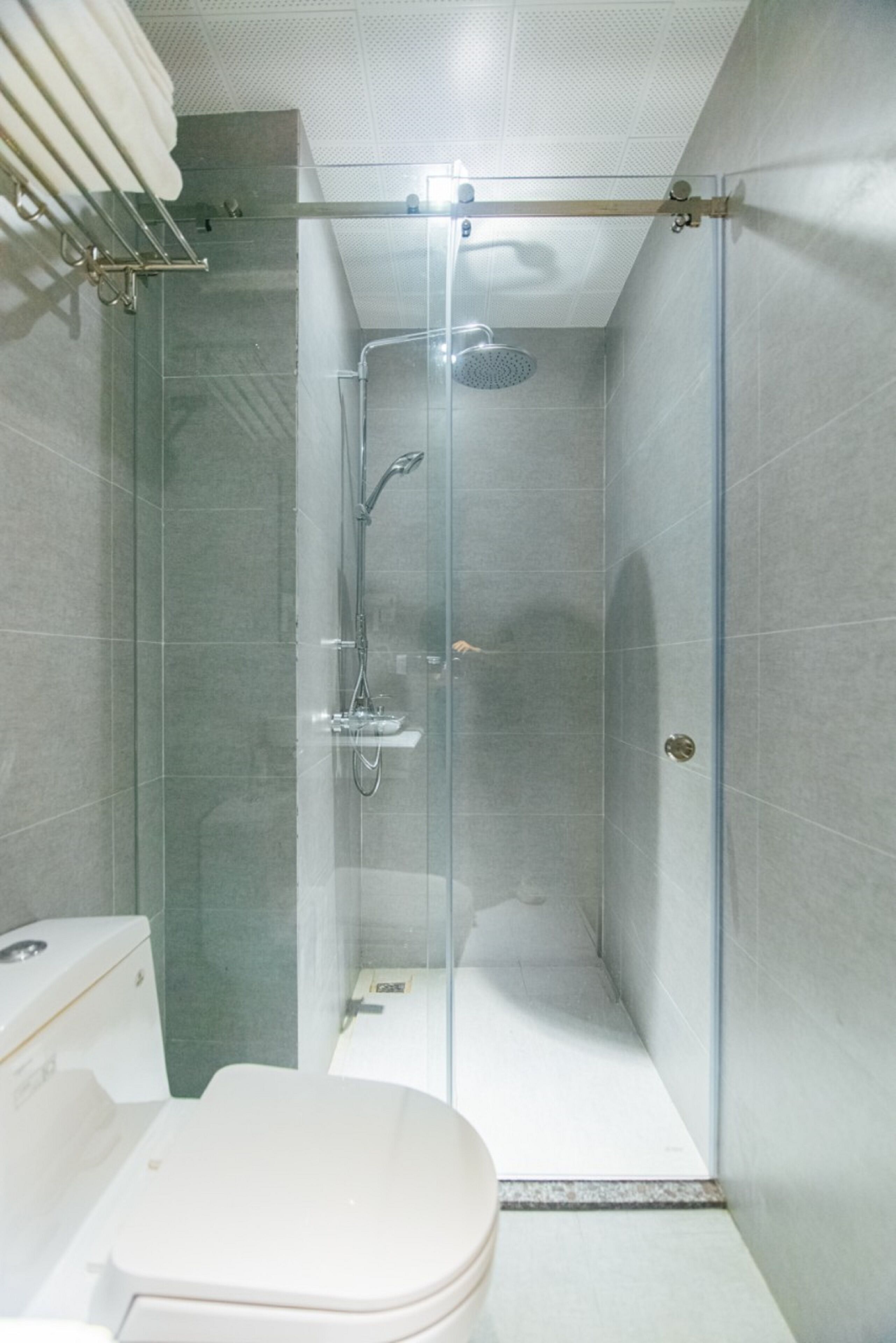 Un baño moderno con ducha de vidrio, inodoro y barra para toallas.
