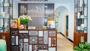 A reception area with a decorative partition, a reception desk, and shelves with various items. - MARUKO HOTEL HA LONG (Bai Chay)