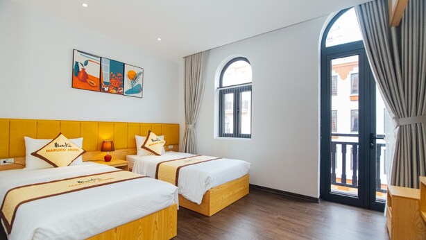 A hotel room with two beds, a large window, and a view of the outside. - MARUKO HOTEL HA LONG (Bai Chay)
