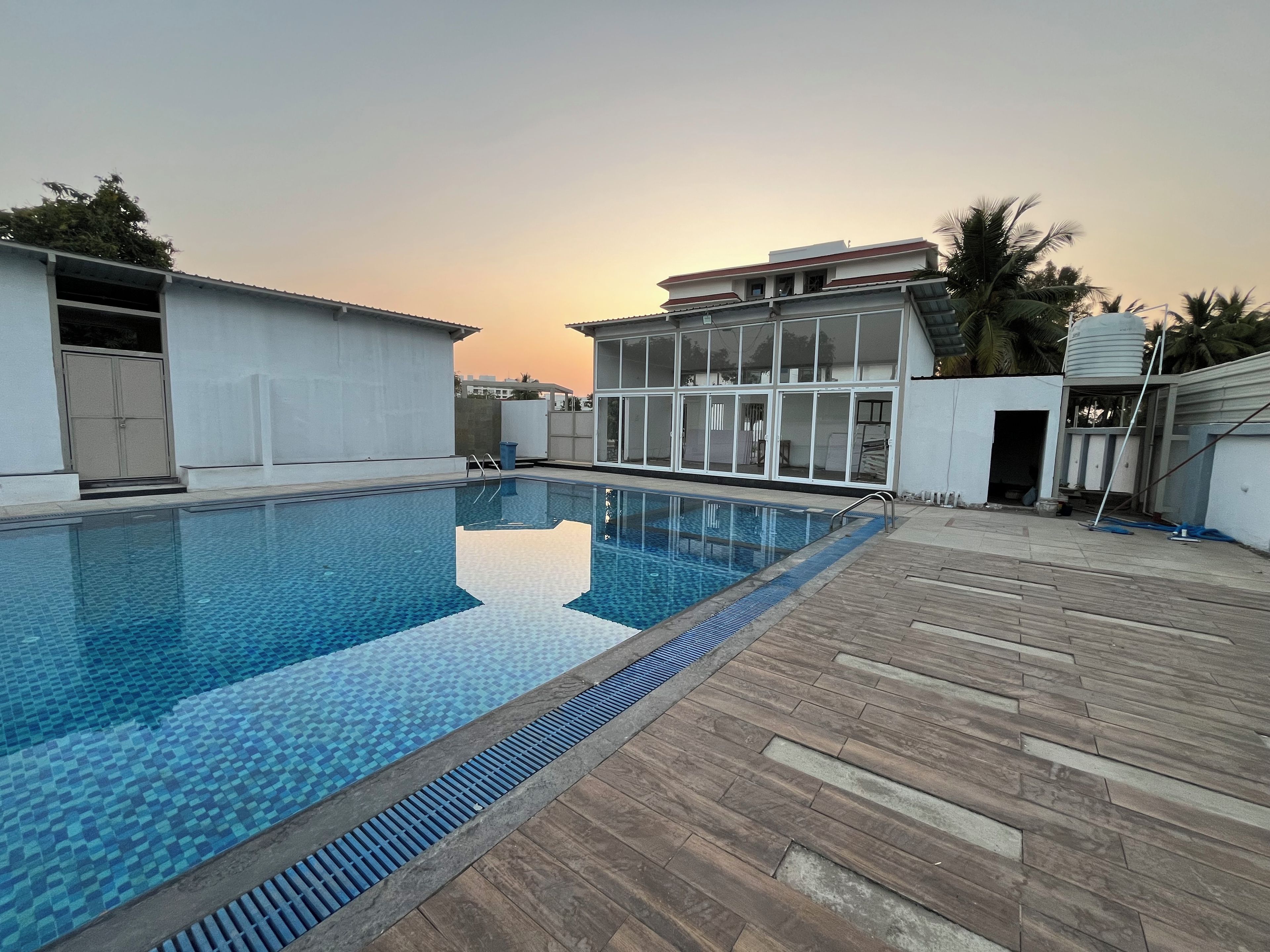 A swimming pool with a tiled deck, surrounded by buildings with large windows and a clear sky.