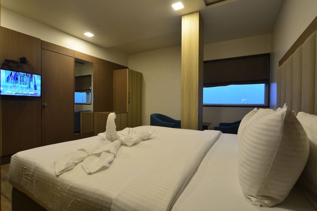 Ein Hotelzimmer mit Bett, Wandfernseher, Fenster mit Ausblick und Holzschrank.