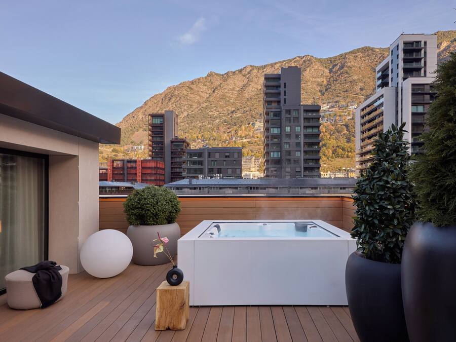 Terraza en la azotea con jacuzzi, mobiliario y plantas en macetas.