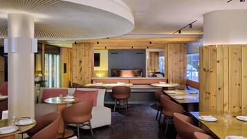 Un restaurante moderno con paneles de madera, mesas redondas y asientos acolchados.