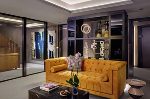 Uma sala de estar moderna com um sofá amarelo, uma mesa de centro de vidro e objetos decorativos.