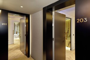 Un pasillo moderno de hotel con puertas numeradas 202 y 203, que dan acceso a las habitaciones.