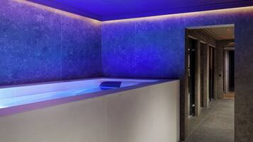 A modern bathroom with a large bathtub, tiled walls, and a hallway leading to other rooms.