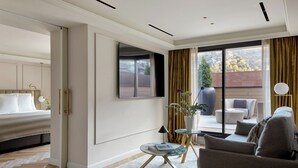 A modern hotel room with a bed, a sofa, a small table with a lamp, a TV, and a view of the outdoors. - MIM Andorra Member of Meliá Collection (Escaldes-Engordany)