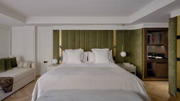 Une chambre d’hôtel avec un grand lit, une table de chevet avec une lampe, un canapé et un mini-bar.