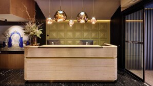 A reception desk with a wooden finish, multiple pendant lights, and a decorative vase. - MIM Andorra Member of Meliá Collection (Escaldes-Engordany)