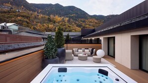A modern outdoor hot tub area with a wooden deck, seating, and a mountain backdrop. - MIM Andorra Member of Meliá Collection (Escaldes-Engordany)