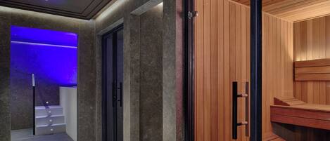 Un interior moderno con zona de sauna, puerta de cristal y pasillo iluminado en azul.