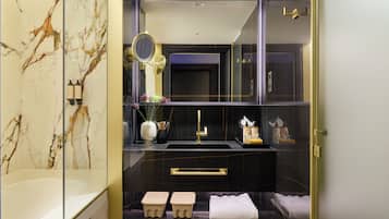 A modern bathroom with a marble vanity, a glass shower enclosure, and a gold-framed mirror.