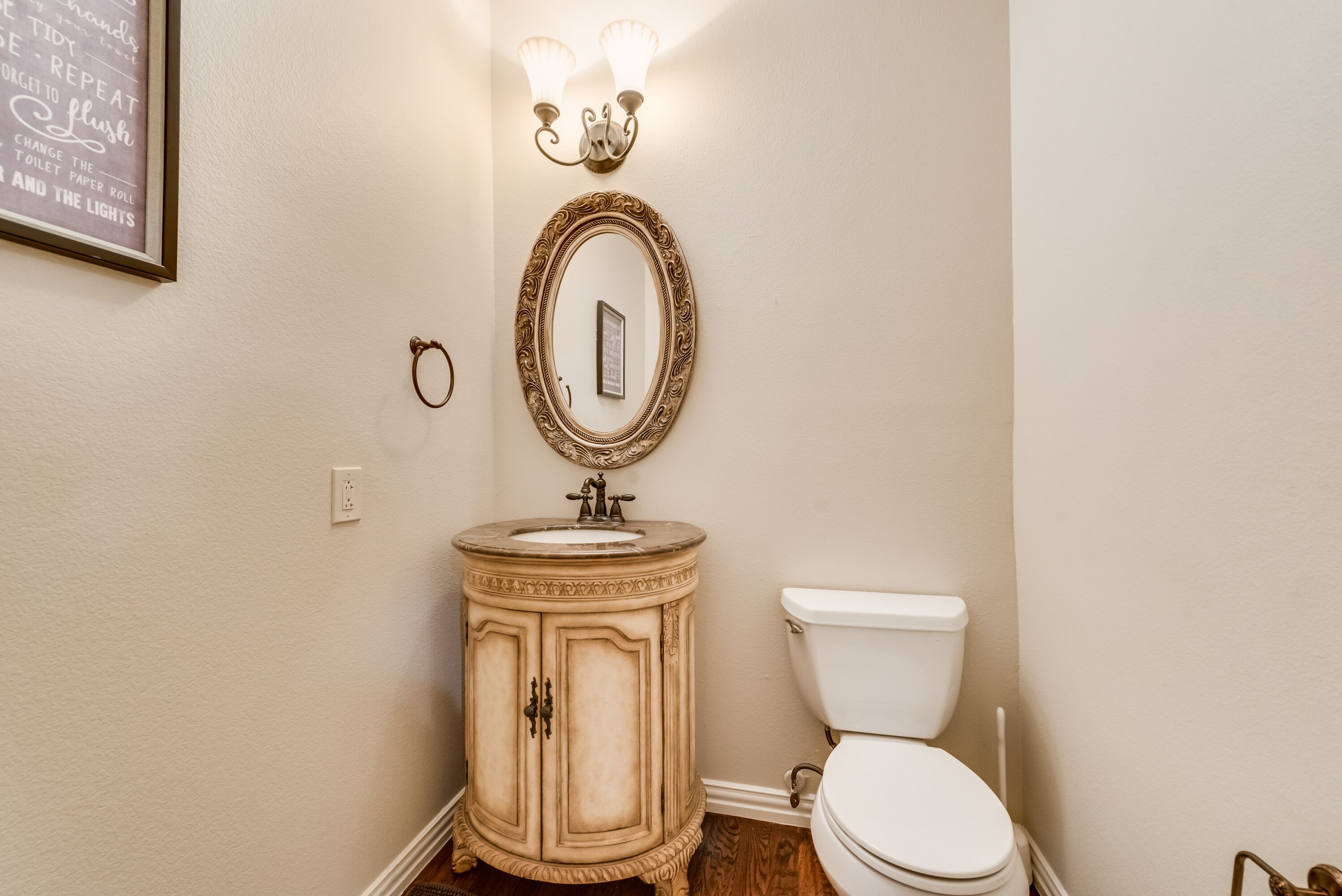 A bathroom with a vanity, sink, mirror, and toilet.