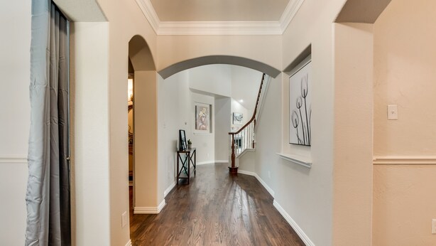 A hallway with wooden flooring, white walls, and a staircase. - New, beautiful 5 BR, 10 beds, near AT&T Stad,Joe Pool, Sixflag, and pet friendly (Grand Prairie)