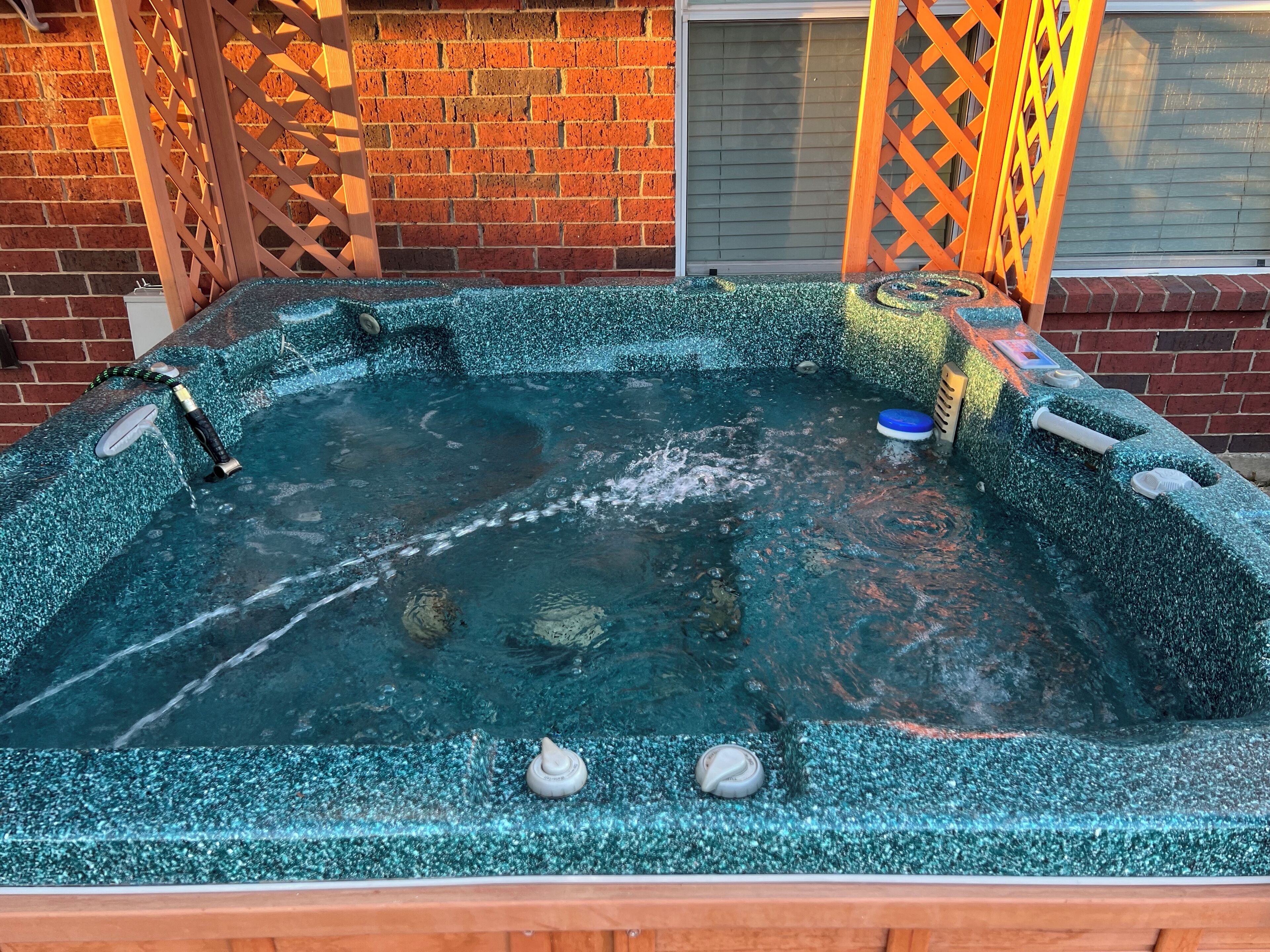 Un jacuzzi con superficie texturizada, calentador incorporado y grifo.