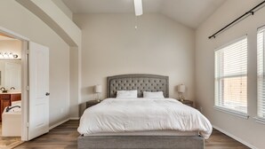A bedroom with a large bed, a nightstand, a lamp, and a window with blinds. - New, beautiful 5 BR, 10 beds, near AT&T Stad,Joe Pool, Sixflag, and pet friendly (Grand Prairie)