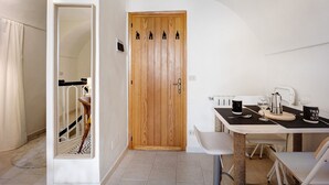 A room with a wooden door, a dining table with chairs, a cat tree, and a white wall.